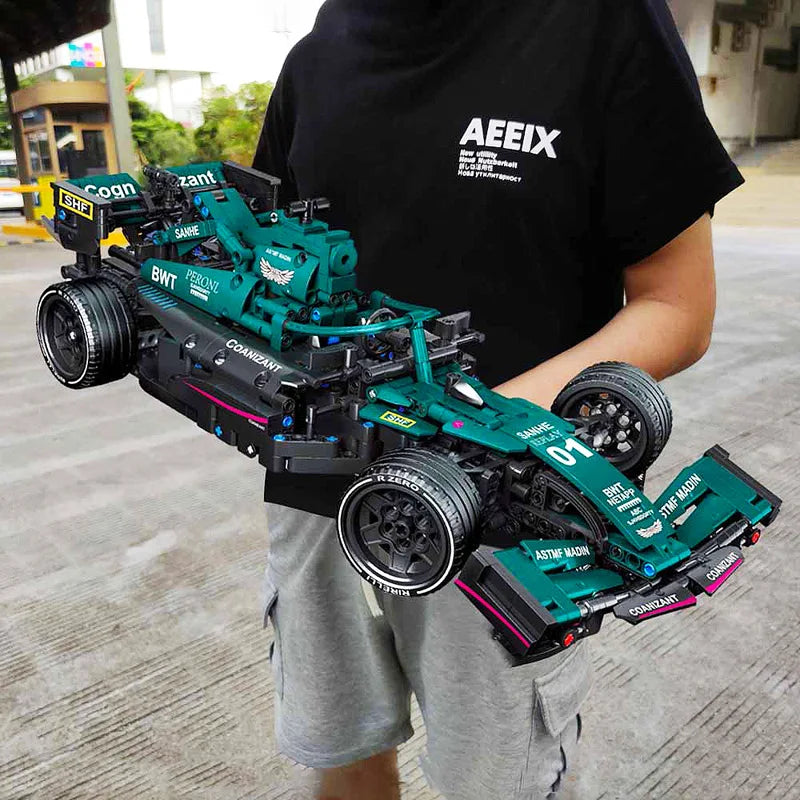 Person holding a green and black toy race car with visible sponsor logos.